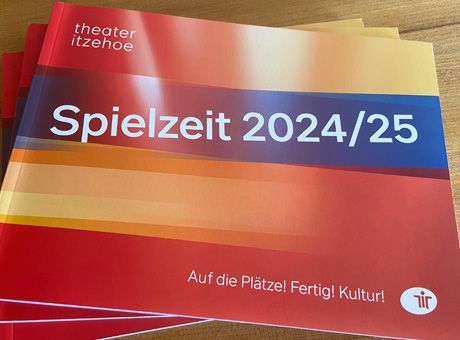 Titelbild eines querformatigen Spielzeitheftes – farbenfrohe transparente Streifen in rot, blau gelb mit einem großen weißen Aufdruck: Spielzeit 2024/25.