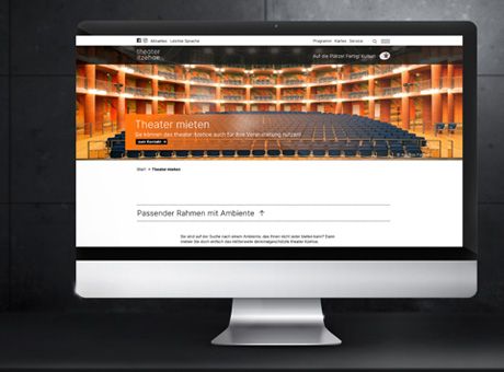 Ein Monitor vor grau-schwarzem Hintergrund aus dem die Webseite des Theater Itzehoe zu sehen ist.